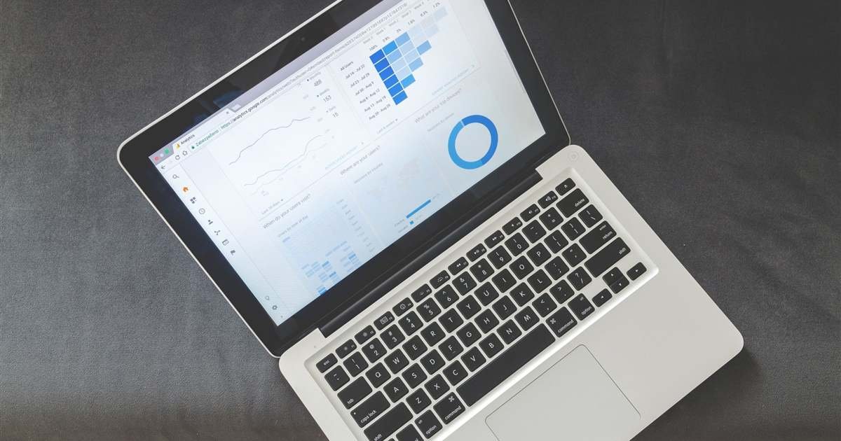 An open laptop on a desk showing an analytics dashboard with line charts and a blue donut chart