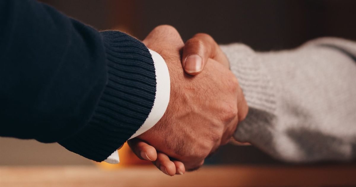Two business people shaking hands across a table