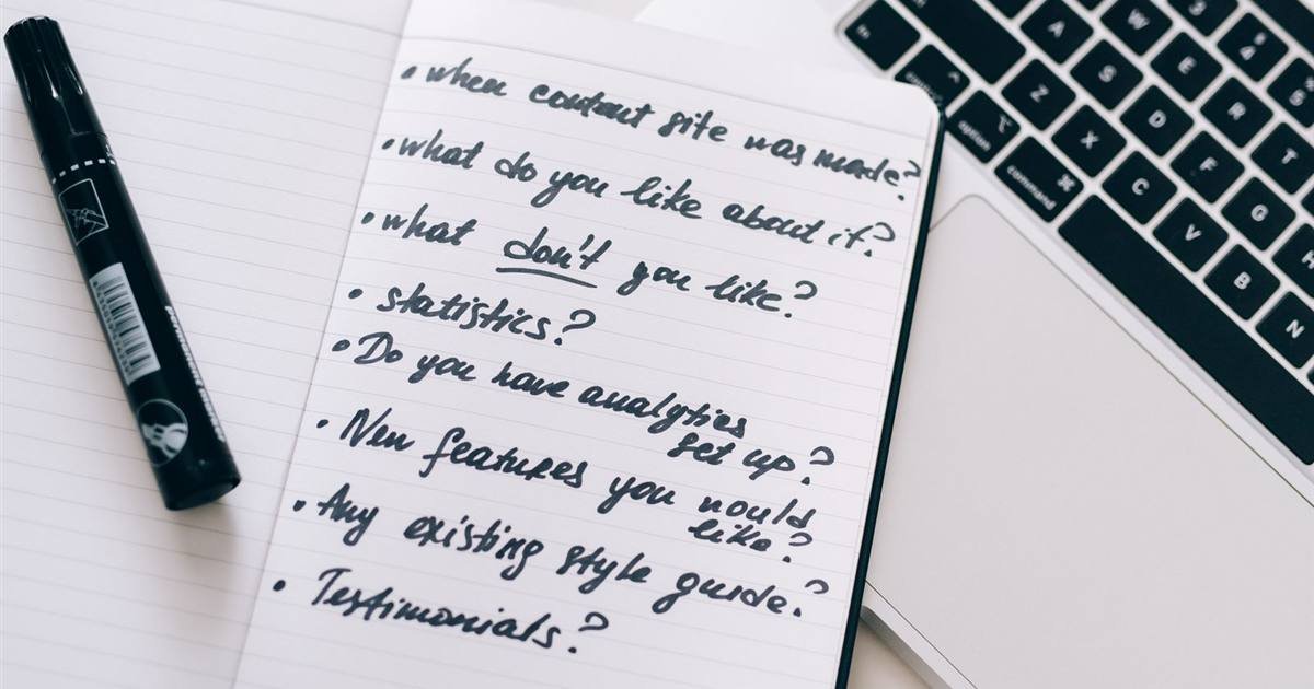 A notebook with handwritten notes and a marker next to a laptop keyboard