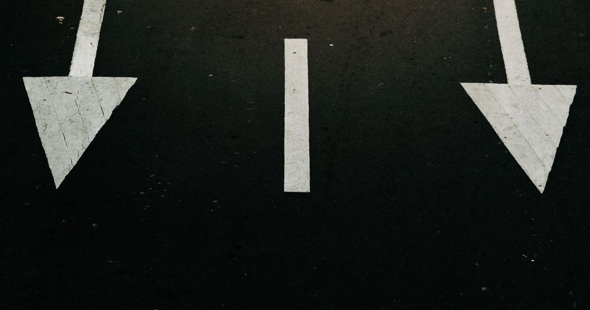 White arrows painted on dark asphalt pointing in different directions
